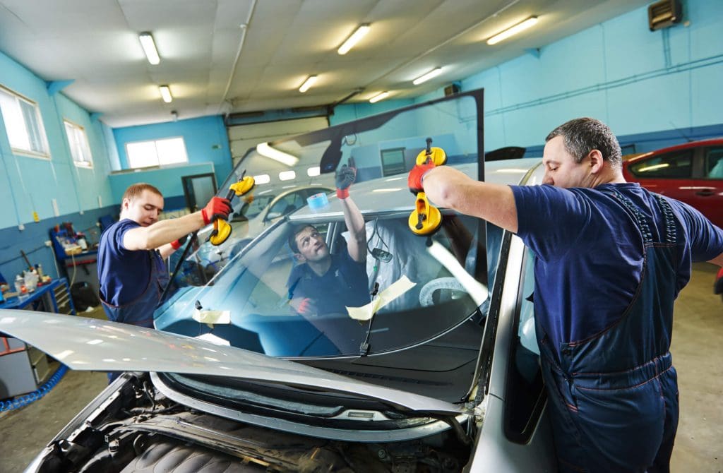 dreamstime_m_40288568 Windshield windscreen replacement. Automobile glaziers workers replacing windscreen or windshield of a car in auto service station garage